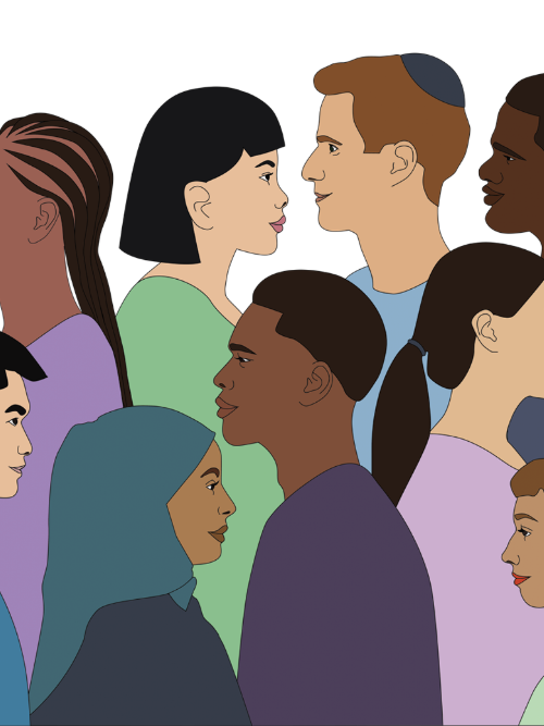 A woman wearing a peach coloured hijab and a lighter pink top, sitting on the sand at the beach in bright daylight. We see her from the back, facing the waves.