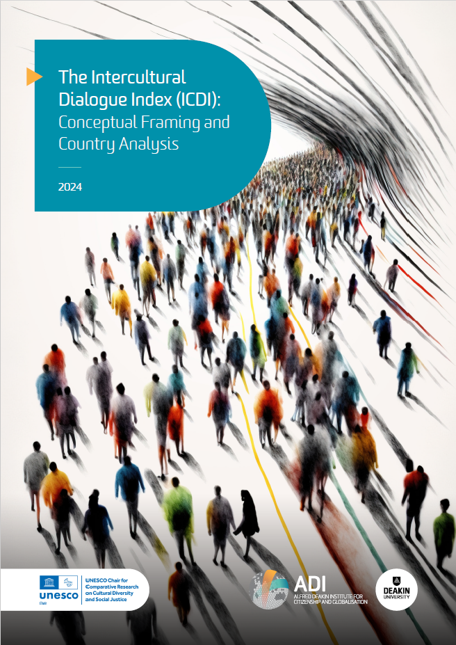 A woman wearing a peach coloured hijab and a lighter pink top, sitting on the sand at the beach in bright daylight. We see her from the back, facing the waves.