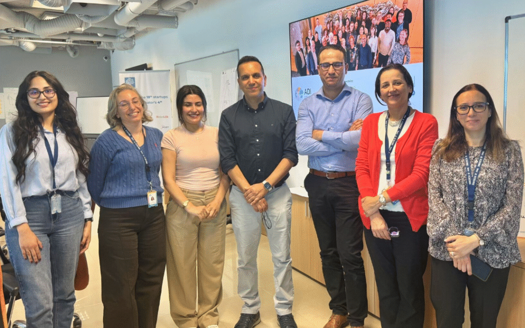 A group of people standing together in a modern university seminar room at South Mediterranean University in Tunisia.